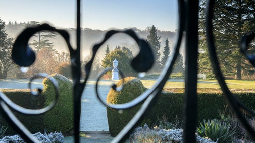 View of the garden at Polesden Lacey through ornate metal gates